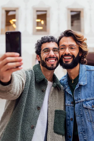 一对快乐的同性恋男人在街上拿着手机拍了一张自拍照片 这幅照片反映了城市生活方式和同性人之间的爱情 — 图库照片