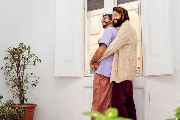 Homosexuell Männliches Paar Lächelt Glücklich Und Umarmt Fenster Ihrem Wohnzimmer — Stockfoto