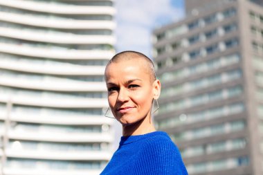 Kel kafalı güçlü bir kadın kameraya bakıp gülümsüyor, şehir yaşam tarzı ve asi tarzı kavramı, metin için kopyalama alanı