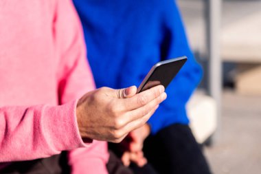 Bir cep telefonunu tutan bir elin dijital dünyada iletişim ve bağlantı teknolojisi kavramını arkadaşınızla paylaştığı bir anı kapatın.