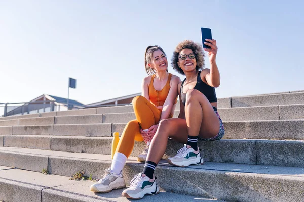 Δύο Γυναίκες Δρομέας Φίλους Λήψη Selfie Φωτογραφία Κινητό Τηλέφωνο Κάθεται — Φωτογραφία Αρχείου