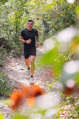 Ormanda koşan bir adamın dikey fotoğrafı, spor anlayışı ve sağlıklı yaşam tarzı, metin için kopyalama alanı