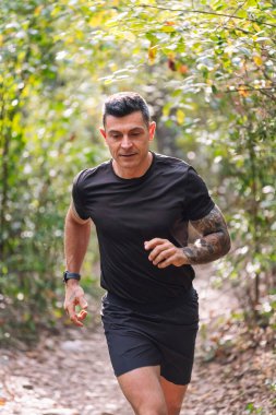 Ormanda koşan bir adamın dikey portresi, doğada spor anlayışı ve sağlıklı yaşam tarzı, metin için kopyalama alanı