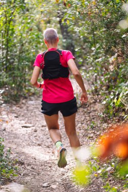 Ormanda koşan bir kadının arkadan görünüşü, spor anlayışı ve sağlıklı yaşam tarzı, metin için kopyalama alanı