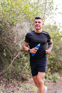 Ormanda koşan bir adamın dikey portresi, doğada spor anlayışı ve sağlıklı yaşam tarzı, metin için kopyalama alanı