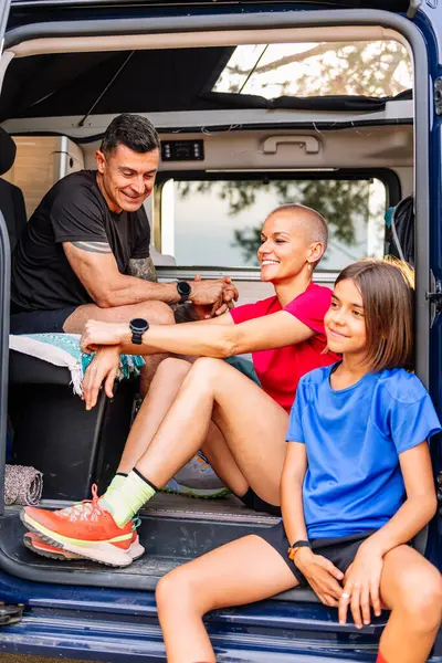 family resting in camper van after doing sports in nature, concept of family outdoor activities and healthy lifestyle