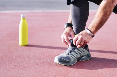 Antrenmandan önce koşu ayakkabısı bağlayan tanınmamış bir sporcu, sağlıklı ve aktif yaşam tarzı kavramı, metin için kopyalama alanı