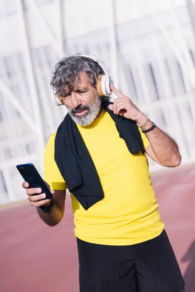 senior sports man listening to music from mobile phone with headphones, concept of active lifestyle in middle age