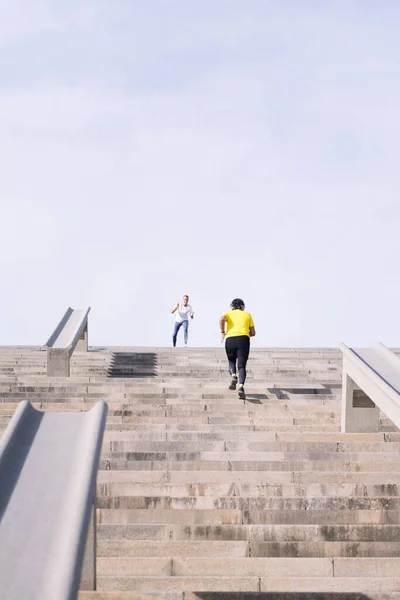 vertical photo of a sports senior man training on stairs while receiving encouragement from personal trainer, concept of active and healthy lifestyle in middle age, copy space for text