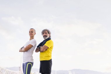 Üst düzey sporcu ve genç kadın kollarını kavuşturup kameraya bakıyor, orta yaşlarda aktif ve sağlıklı yaşam biçimi kavramı, metin için kopyalama alanı