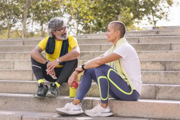 senior sports man rests chatting with his personal trainer after a hard workout, concept of healthy and active lifestyle in the middle age