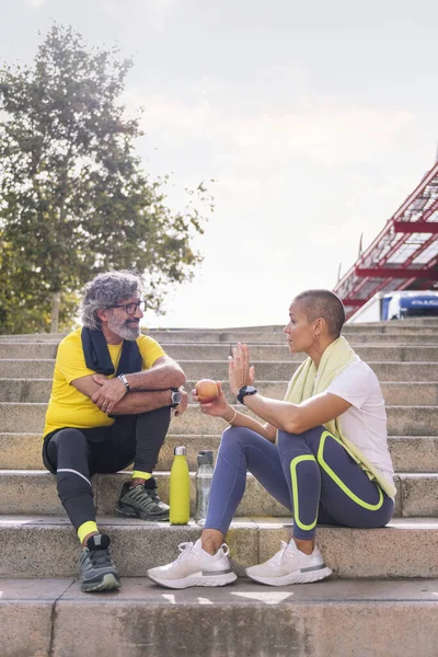 senior sports man rests chatting with his personal trainer after a hard workout, concept of healthy and active lifestyle in the middle age, copy space for text