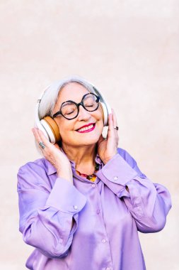 Gülümseyen, gözlüklü, kulaklıklarıyla müzik dinleyen yaşlı kadın, yaşlıların boş ve aktif yaşam tarzı konsepti, metin için kopyalama alanı