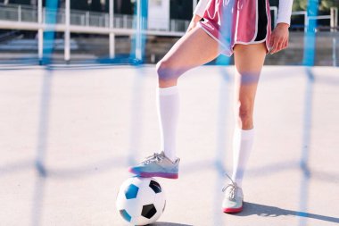 Şehir sahasında futbol topuna basan tanınmamış bir bayan futbolcunun bacakları, spor anlayışı ve aktif yaşam tarzı