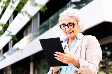 Olgun bir kadın kentte dijital tablet kullanırken mutlu gülümsüyor. Yetişkinlikte kentsel yaşam biçimi kavramı ve teknoloji iletişimi. Metinler için metin alanı.