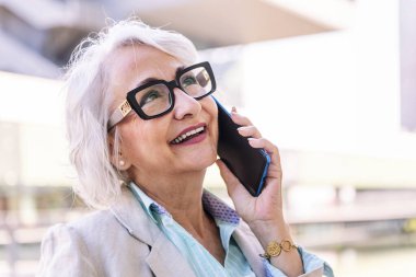 Cep telefonuyla konuşurken mutlu gülümseyen şık olgun bir kadının portresi, iletişim teknolojisi konsepti ve yetişkinlikte modern yaşam tarzı, metin için telif alanı