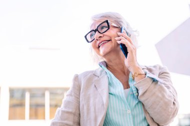 Cep telefonuyla konuşurken mutlu gülümseyen şık olgun bir kadının portresi, iletişim teknolojisi konsepti ve yetişkinlikte modern yaşam tarzı, metin için telif alanı