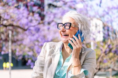 Mutlu bir şekilde gülen olgun bir kadının portresi cep telefonu, iletişim teknolojisi konsepti ve yetişkinlikte modern yaşam tarzı, metin için metin metni için telif alanı