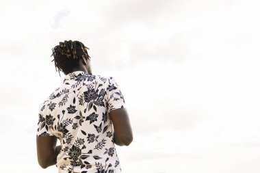 Arka planda gökyüzü, özgürlük ve yaşam tarzı kavramı, metin için kopyalama alanı olan çiçek gömlekli şık bir Afro-Amerikan erkeğinin arka planı