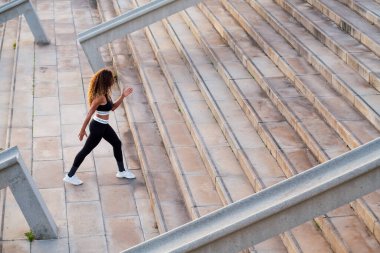 Spor giysilerinde, spor yaparken, şehir merdivenlerinde yürürken, şehir sporu konsepti ve sağlıklı yaşam tarzında fark edilemeyen hızlı koşucunun yüksek açılı arka görüntüsü.