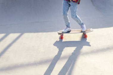 Yazın güneşli bir günde kaykayın üzerinde kot pantolon ve spor ayakkabıyla tanınmaz hale gelmiş bir patenci.