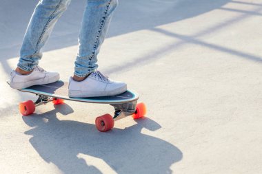 Yazın güneşli bir günde kaykayın üzerinde kot pantolon ve spor ayakkabıyla tanınmaz hale gelmiş bir patenci.