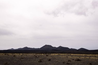 Cuervo volkanı manzarası ve Tinajo 'daki bulutlu gökyüzü altındaki engebeli dağlar Kanarya Adaları İspanya' daki Lanzarote konsepti, kurak manzara ve macera yolculuğu.
