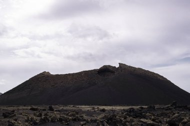 Cuervo volkanı manzarası ve Tinajo 'daki bulutlu gökyüzü altındaki engebeli dağlar Kanarya Adaları İspanya' daki Lanzarote konsepti, kurak manzara ve macera yolculuğu.