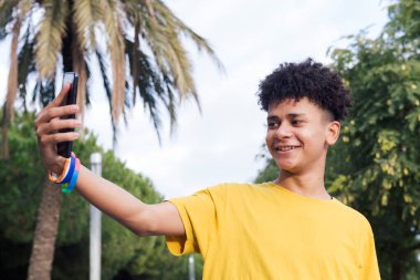 Latin erkek gülümseyen mutlu cep telefonuyla selfie çekimi, gençlik yaşam tarzı ve iletişim teknolojisi kavramı