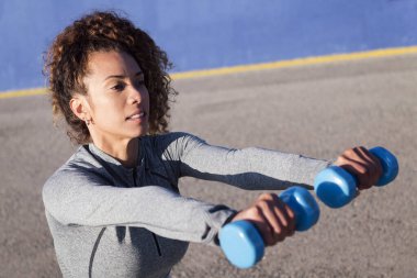Spor giyimli bayan sporcu, asfalt yolda çalışırken dambıllarla çalışıyor, şehir sporu ve sağlıklı yaşam tarzı kavramı, metin için kopya alanı