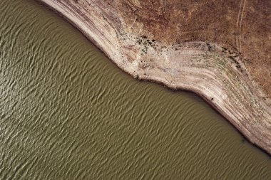 Taşlı kıyılarda akan dalgalı su yüzeyi ve kurumuş yüzey, çevre ve ekoloji kavramına sahip drone görüntüsü.
