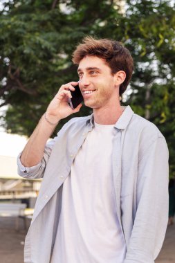 Adam mutlu bir şekilde yürürken gülümsüyor cep telefonuyla konuşuyor, iletişim teknolojisi ve kentsel yaşam tarzı kavramı