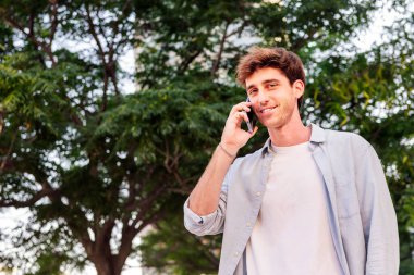 Adam mutlu bir şekilde yürürken mutlu bir şekilde gülümsüyor cep telefonuyla konuşuyor, iletişim teknolojisi ve şehir yaşam tarzı kavramı, metin için kopyalanmış alan