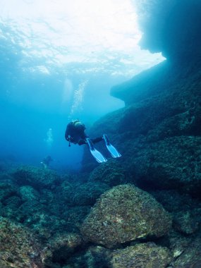 Dalgıçlar kristal berrak suda dalıyorlar güneş deniz yüzeyine yansıyor, eğlence amaçlı tüplü dalış ve sualtı macerası kavramı