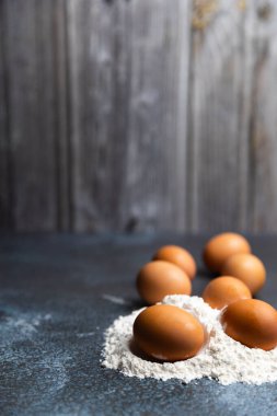 Kırsal, sanatsal bir his için hafif bir un tabakası ile tozlanmış, dokusu gri bir zemine saçılmış taze kahverengi yumurta koleksiyonu..