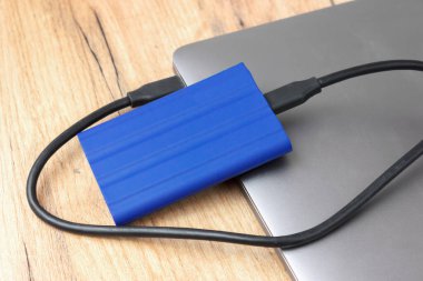 Laptopta mavi harici sabit disk, ahşap arka plan. Yaratıcı ve ticari projeler için mükemmel.