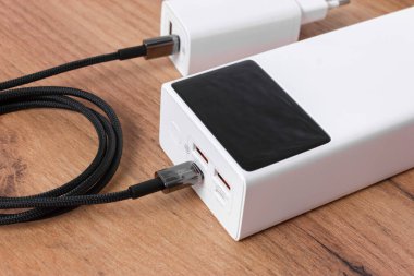 Beyaz enerji bankası ve tahta bir masa yüzeyindeki kablo. Çoklu amaçlar için çok yönlü resim