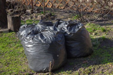 Bahçedeki çöp torbaları, temizliği ve atık yönetimi sembolize ediyor. Yaratıcı ve ticari projeler için mükemmel.