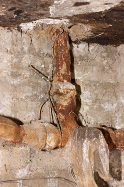 Çatlak beton duvara dayanmış paslı boru, çürüme gösteriyor. Yaratıcı ya da profesyonel projeler için harika