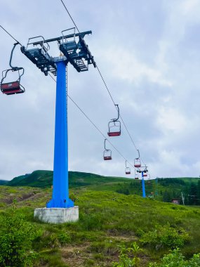 Gökyüzü bulutlu yeşil tepelerin üzerinde kayak kaldırma. Yaratıcı ya da profesyonel projeler için harika