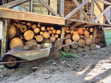 Kırsal bir ahşap yapının dışında yakacak odun ve el arabası yığını. Yaratıcı ve ticari projeler için mükemmel.