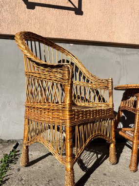 Hasır sandalye ve masa güneş ışığında, arka planda bir duvara karşı. Yaratıcı ve ticari projeler için mükemmel.