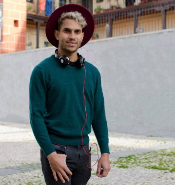 Kulaklıklı ve kırmızı şapkalı genç adam şehirde.