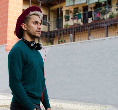 Kulaklıklı ve kırmızı şapkalı genç adam şehirde.