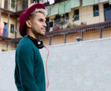 Kulaklıklı ve kırmızı şapkalı genç adam şehirde.