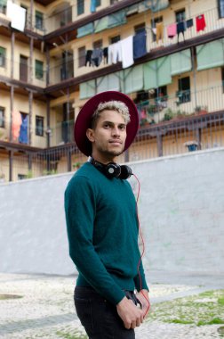 Kulaklıklı ve kırmızı şapkalı genç adam şehirde.