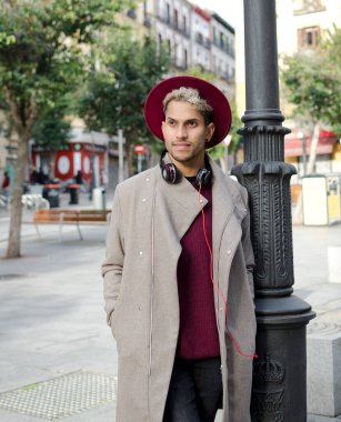 Kulaklıklı ve kırmızı şapkalı genç adam şehirde.