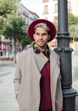 Kulaklıklı ve kırmızı şapkalı genç adam şehirde.