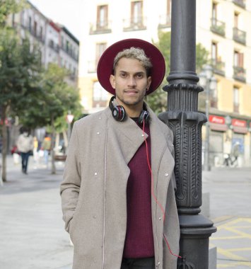 Kulaklıklı ve kırmızı şapkalı genç adam şehirde.