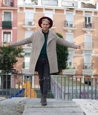 Gri ceketli, kırmızı şapkalı, sokakta dengeyi sağlayan genç bir model.